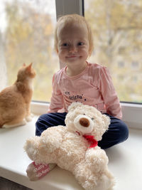 Portrait of cute baby girl sitting by window at home