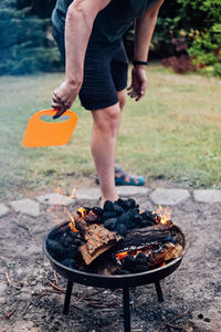 How to use a charcoal grill. man with plastic bbq hand fan near charcoal grill fire. barbeque