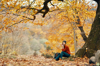 Young woman sitting on road during autumn