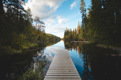 Wooden pier and still river reflect colourful autumn forest.  autumn in hossa national park, finland