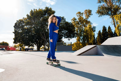 Cheerful caucasian woman with blonde hair skating in urban setting