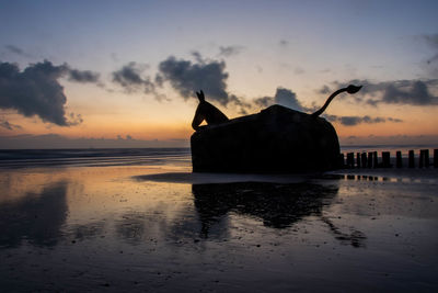 Silhouette boat on beach against sky during sunset