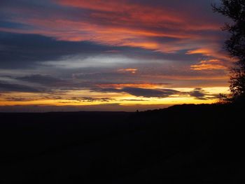 Scenic view of silhouette landscape against dramatic sky during sunset