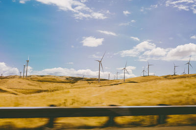 Wind turbines in farm against sky