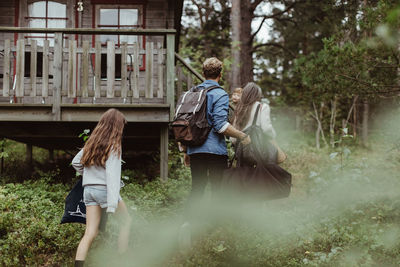 Rear view of girl with family walking towards house in forest