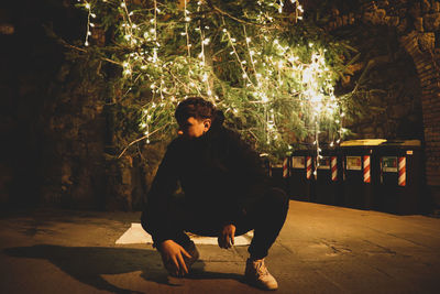 Full length of young man looking at camera at night