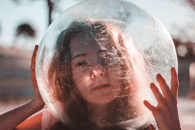 Close-up portrait of young woman wearing glass helmet in head during sunny day