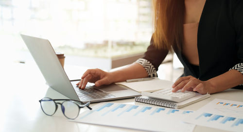 Midsection of businesswoman working on table