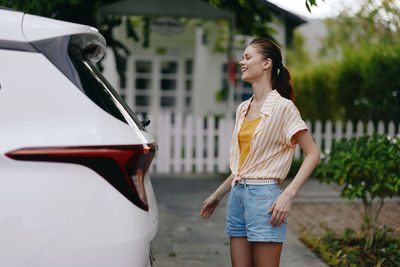 Young woman standing against car