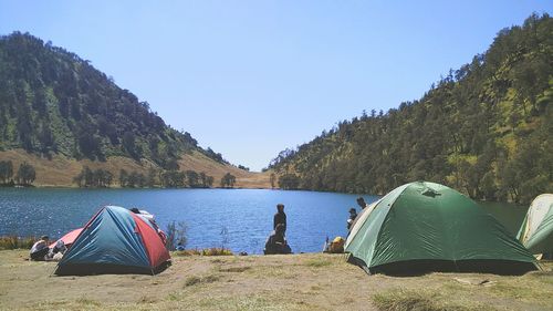 Tent on mountain by lake against sky