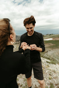 Young couple holding smart phone against sky