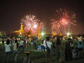 People watching firework exploding over wat phra kaew against sky