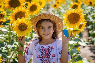 Portrait of girl holding heart shape in sunflower field