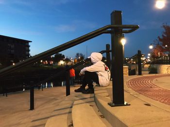 Man sitting in illuminated city at night