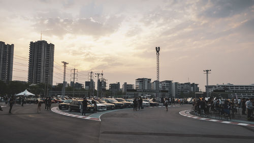 City street by buildings against sky during sunset