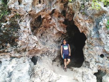 Full length portrait of young woman standing in cave