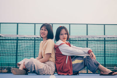 Portrait of smiling young couple sitting on railing