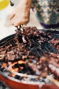 Close-up of person preparing food on barbecue grill