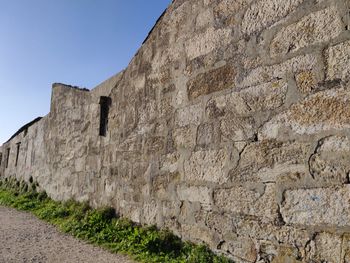 Low angle view of brick wall against clear sky