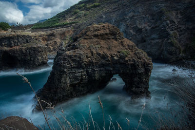 Rock formation in sea against sky