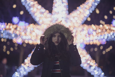 Portrait of woman standing against illuminated lights