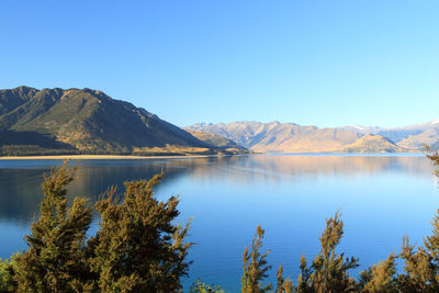 Scenic view of lake and mountains against clear blue sky