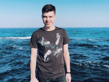Portrait of smiling man standing in sea against sky