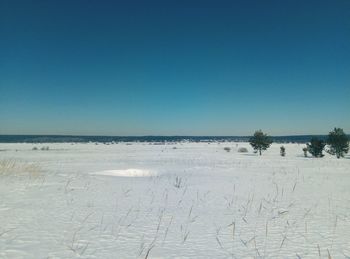 Scenic view of snow covered land against clear blue sky