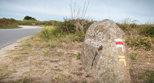 Road sign on field against sky