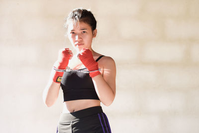 Young woman standing against wall