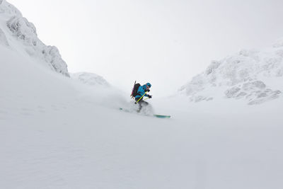 Young man skiing on snowcapped mountain against sky