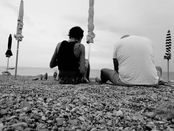 Rear view of people sitting on beach