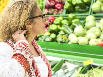 Side view of woman with vegetables for sale at market stall