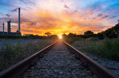 Surface level of railroad tracks against sky during sunset