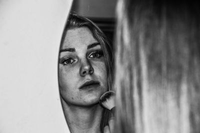 Reflection of woman applying make-up in mirror at home