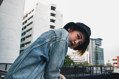 Low angle view of woman standing against buildings in city