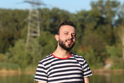 Portrait of smiling young man standing against trees