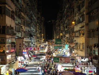 High angle view of people on street amidst buildings in city at night