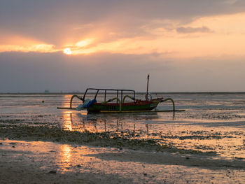 Fishing boat on sea against sky during sunset