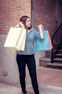 Full length of woman standing against brick wall