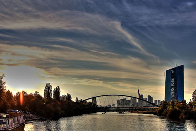 Bridge over river against cloudy sky