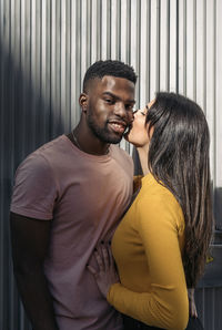 Man kissing woman against wall