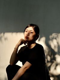 Portrait of young woman looking away against wall