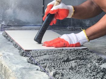 Cropped image of hands holding tile on floor