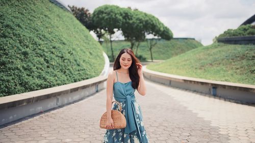 Portrait of smiling woman standing on footpath