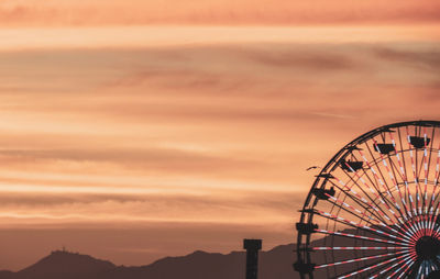 Low angle view of ferris wheel against sky at sunset