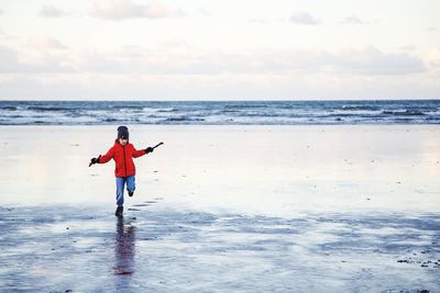 Rear view of man standing on beach against sky