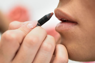 Beautician applying lipstick on woman lips in salon