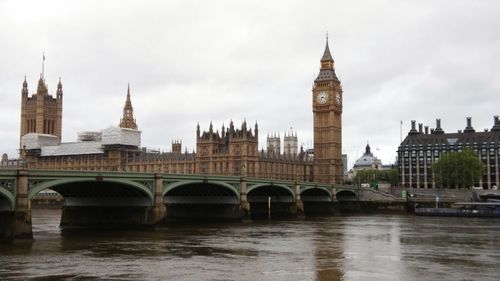 Bridge over river in city against sky