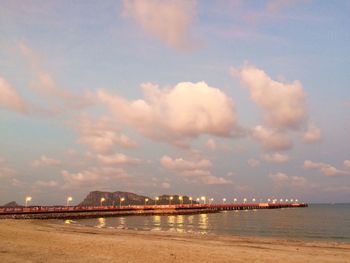 Scenic view of illuminated city by sea against sky